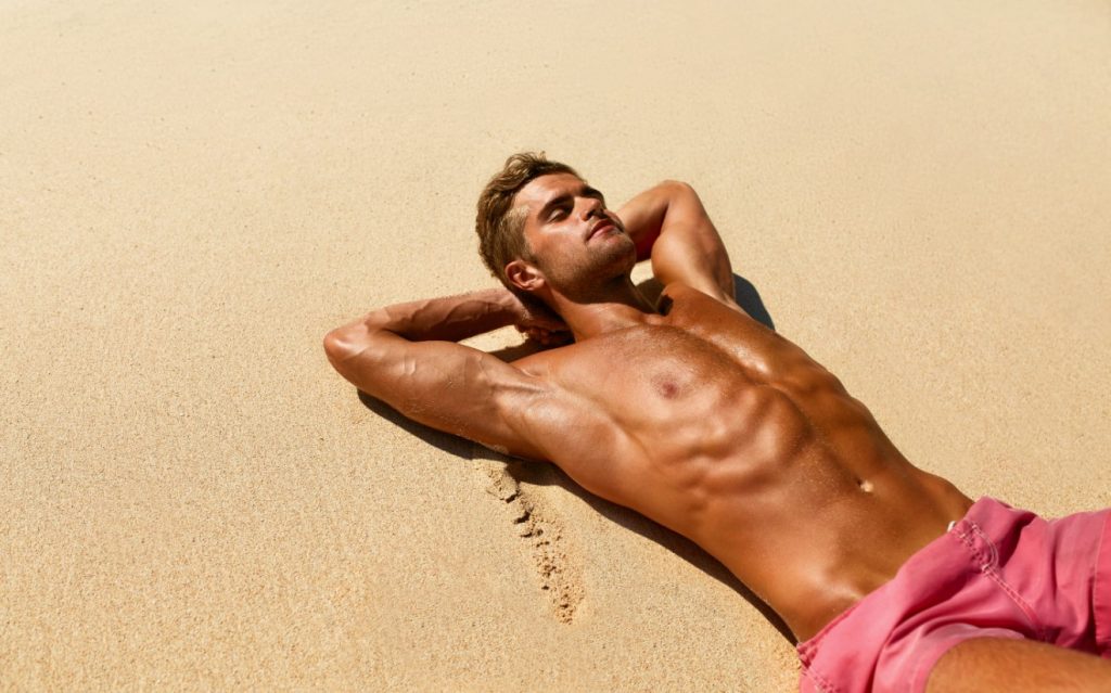 άνδρας κάνει ηλιοθεραπεία στην παραλία