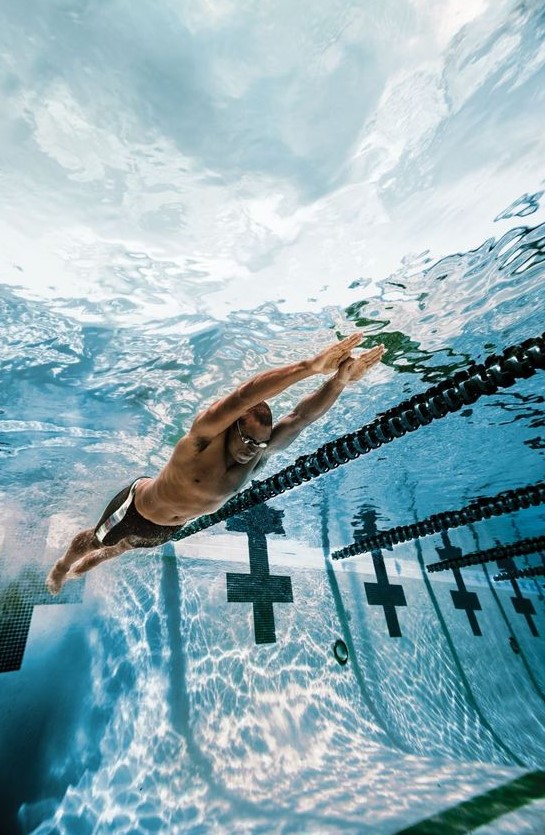άντρας κολυμπάει σε πισίνα κολυμβητηρίου